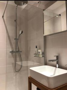 La salle de bains est pourvue d'un lavabo blanc et d'une douche. dans l'établissement Deauville centre, plage, casino et hippodrome, à Deauville