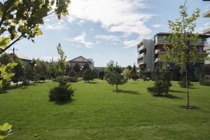 un parc verdoyant avec des arbres et un bâtiment dans l'établissement Airport Residence - Across from Otopeni Airport, à Otopeni