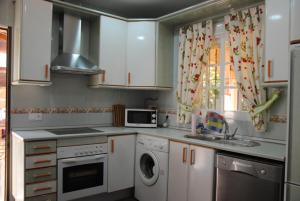 een keuken met witte kasten en een wasmachine en wastafel bij Villa Solea in Chiclana de la Frontera