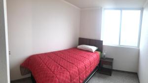 Un pequeño dormitorio con una cama roja y una ventana en Horizonte infinito, en Viña del Mar