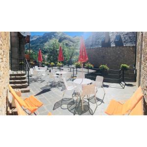 a patio with tables and chairs and red umbrellas at Aparthotel Es de Don Joan in Unha