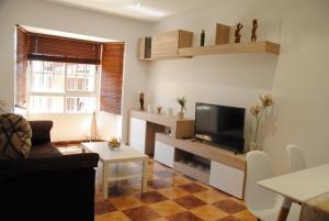 een woonkamer met een bank en een tv bij Villa Solea in Chiclana de la Frontera
