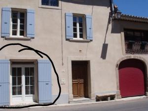 studio cosy en PROVENCE في Camaret-sur-Aigues: مبنى بنوافذ مقفلة ازرق وكراج احمر