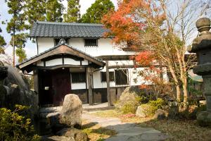 une maison japonaise avec une porte dans un jardin dans l'établissement Kurokawa Mori no Cottage, à Minamioguni