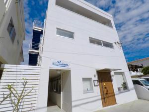 a white building with a door in front of it at Shima Stay holoholo in Zamami