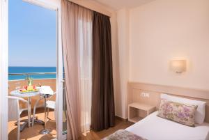 a hotel room with a bed and a table and a balcony at Sunray Hotel in Limenaria