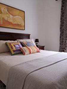 a bed with two pillows and a painting on the wall at El Sabinar in Vallehermoso