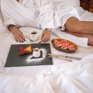 The Oberoi Beach Resort, Sahl Hasheesh في الغردقة: امرأة في السرير مع طبق من الطعام وكوب من القهوة