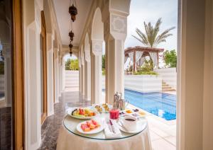 a table with a tray of food on it next to a pool at The Oberoi Beach Resort, Sahl Hasheesh in Hurghada