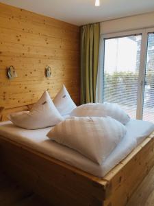 un letto con cuscini bianchi in una stanza con finestra di Apart Mare a Sölden