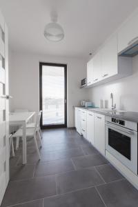 a kitchen with white cabinets and a table and a dining room at Apartament przy sopockiej plaży in Sopot