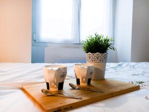 a wooden tray with two spoons and a plant on a bed at SWEET APARTMENT CARRIERES - 1 chambre - 4 Pers - Wifi in Carrières-sur-Seine