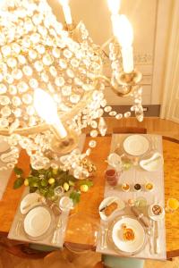 a dining room table with white dishes and lights at Residenza D'Epoca -Santa Caterina in Pisa