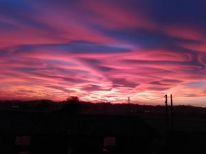 un coucher de soleil avec des nuages roses et violets dans le ciel dans l'établissement Agriturismo Cascina Aguzza, à Oleggio