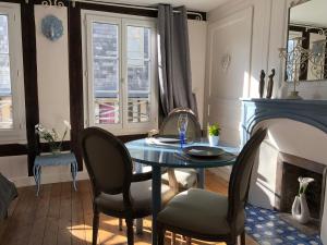 ein Esszimmer mit einem Tisch, Stühlen und einem Kamin in der Unterkunft LA PARENTHÈSE DU CAPUCIN in Honfleur