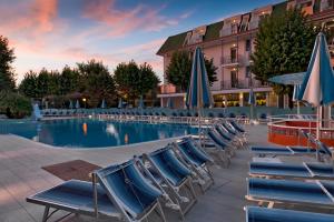 un gruppo di sedie e ombrelloni accanto a una piscina di Suite Apartment Exclusive a Bellaria-Igea Marina