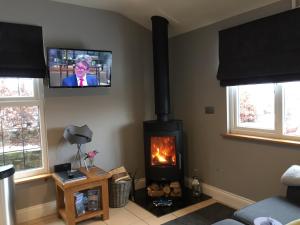 een woonkamer met een open haard en een tv aan de muur bij Summer House, Glassonby in Penrith