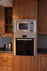 um micro-ondas na cozinha com armários de madeira em Holmgård em Süderholm