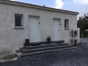 a house with three white doors and stairs in front at Studio Marymer in Cervione