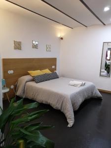 1 dormitorio con 1 cama grande y cabecero de madera en Apartamentos 14DeSande, en Cáceres