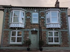 a brick house with white windows and a door at Lion House Bed & Breakfast with Restaurant in Combe Martin