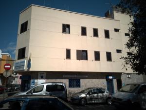 un edificio blanco con coches estacionados frente a él en UNION 64 en Vecindario