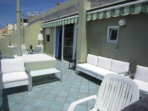 un patio con sedie bianche e un tavolo sul balcone. di Ático en primera linea Las Canteras a Las Palmas de Gran Canaria Altre 5 foto