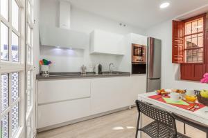 kuchnia z białymi szafkami i stołem z talerzem żywności w obiekcie Centro, 3BD y 2BA, 1min Catedral, duplex de lujo w Sewilli
