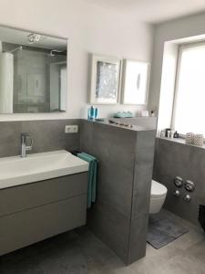 a bathroom with a sink and a toilet and a mirror at Moderne Ferienwohnung direkt in Landsberg am Lech in Landsberg am Lech