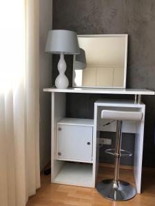 a white desk with a lamp and a stool at Moderne Ferienwohnung direkt in Landsberg am Lech in Landsberg am Lech