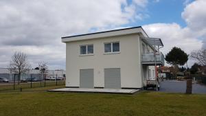 a white house with a garage on a grass field at FeWo "Am Auwald" in Leipzig