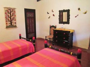 San José PurúaにあるHotel Agua Blancaのベッド2台、鏡、ドレッサーが備わる客室です。