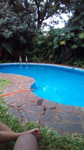 une personne assise à côté d'une piscine bleue dans l'établissement Posadas la hermosa, à Posadas