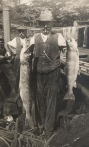 an old photo of a man holding two fish at zum Fischerhaus in Konstanz