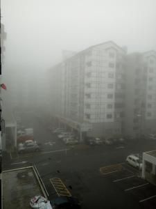 a foggy parking lot in a city with tall buildings at SKY PURPLE @CH in Tanah Rata