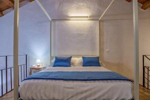 a bedroom with a large bed with blue pillows at Le Maestranze Deluxe Rooms in Sciacca