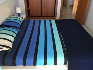 a bed with a blue and black striped blanket at Fuengirola Apartment in Fuengirola