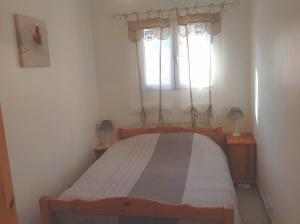 Dormitorio pequeño con cama y ventana en La petite maison en La Gaude