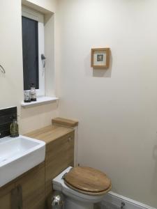 a bathroom with a wooden toilet and a sink at 1 Balnakeil, Kirk Road in Oban