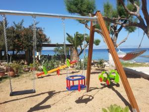 a playground with swings in the sand near the ocean at Irides in Souvala