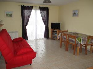 a living room with a red chair and a table and a television at Logement Soulac sur mer in Soulac-sur-Mer