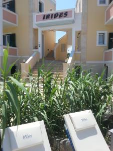 a hotel with two white benches in front of a building at Irides in Souvala
