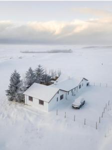 dom na śniegu z samochodem zaparkowanym obok niego w obiekcie Hellatún Guest House! w mieście Hella