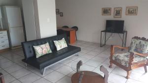 a living room with a black couch and two chairs at 2 Bedroom Cottage in Midrand
