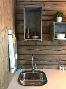 a sink in a kitchen with a wooden wall at Drolsum Gård in Vikersund