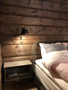 a bedroom with a wooden wall with a bed and a lamp at Drolsum Gård in Vikersund