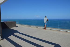 een persoon op een balkon met uitzicht op de oceaan bij Castelsardo Miramare 10 - 6 posti in Castelsardo
