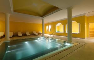 a swimming pool in a large room with chairs at The Yeatman in Vila Nova de Gaia