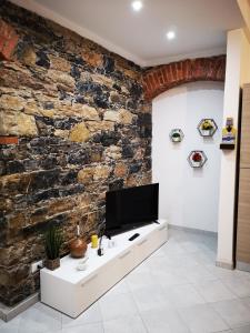 sala de estar con pared de piedra y TV en Revel Apartments Central Station Cinque Terre, en La Spezia