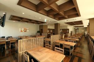 a dining room with wooden tables and chairs at Hotel Route-Inn Shinshiro in Shinshiro